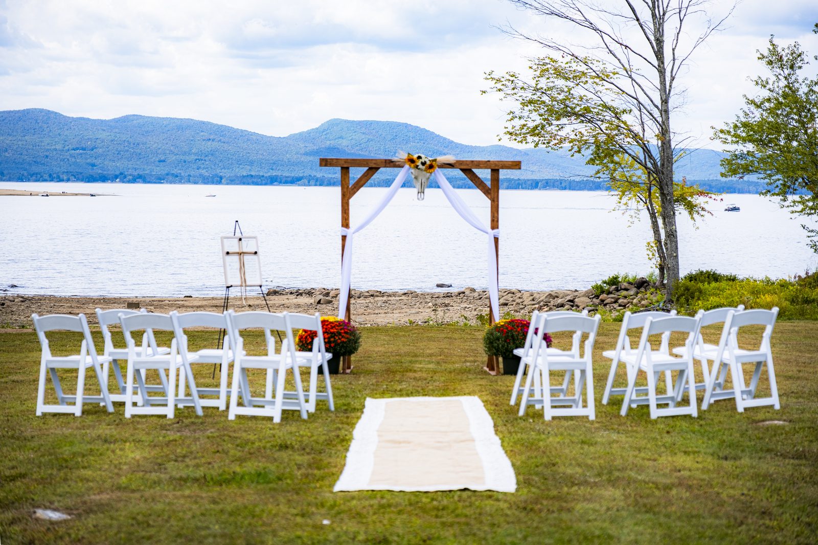 Outdoor lakefront wedding ceremony setup with white floral arch